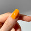 Hand with a bright orange nail against a neutral background